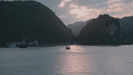 Luftaufnahme-Eines-Bootes,-Das-Bei-Sonnenuntergang-In-Der-Bucht-Von-Lan-Ha-In-Vietnam-Segelt