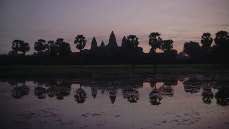 Dawn-breaks-over-Angkor-Wat-with-a-vibrant-sky-reflecting-in-the-water,-serene-and-majestic,-timelapse