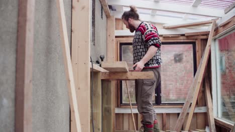 Man-Fixing-Wood-Plank,-Building-Greenhouse---Wide-Shot