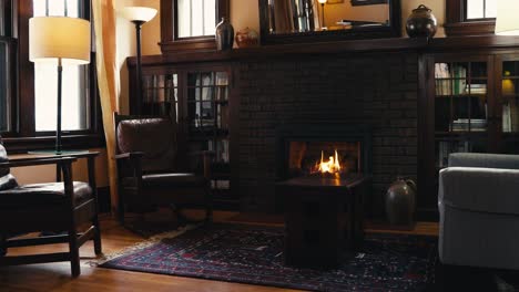 medium-tight-shot-of-a-gas-fireplace-lit-in-the-living-room-of-a-home-in-front-of-a-coffee-table-with-2-leather-chairs-and-a-couch