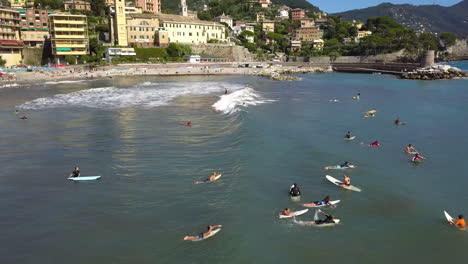 Surfers-on-the-coastline-of-Recco,-sunny-day-in-Liguria,-Italy---Aerial-view
