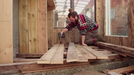 Mann-Mit-Bohrmaschine-Beim-Bau-Eines-Holzbodens-Für-Das-Gewächshaus---Nahaufnahme