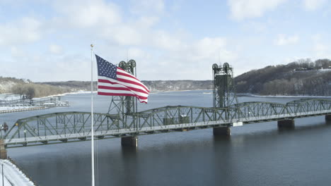 Aerial-orbit-around-waving-USA-flag-and-historic-lift-bridge-in-Stillwater