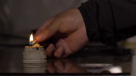 candle-lit-by-a-man's-hand-with-out-of-focus-background,-power-outage-concept