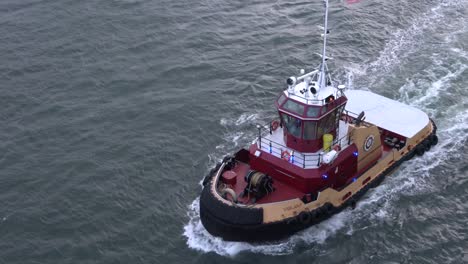 Red-and-yellow-tugboat-is-along-an-ocean-going-vessel