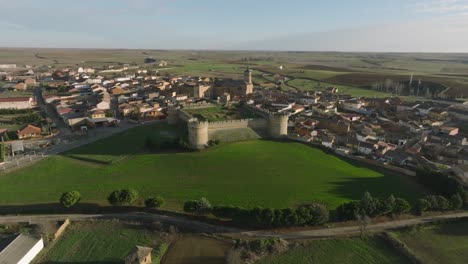 Aerial-castle-fortress-village-green-meadows-Grajal-de-Campos-in-Spain,-daylight-skyline