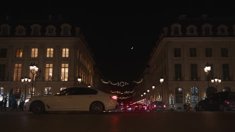 Night-low-angle-view-of-the-street-with-slow-moving-traffic-and-illuminated-Christmas-decorations-in-Paris
