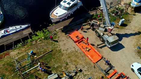 Lowering-luxury-boat-into-the-water-with-autocrane,-aerial-view