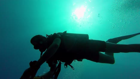 Form-Eines-Tauchers,-Der-In-Der-Silhouette-Mit-Kontrastierendem-Hellgrünem-Hintergrund-Schwimmt-Und-Blasen-Atmet