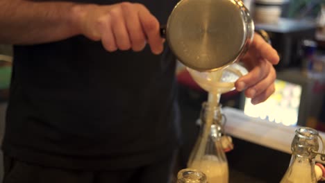 Seitenansicht-Eines-Barkeepers,-Der-Zitronensaft-Durch-Einen-Plastiktrichter-In-Eine-Flasche-Gießt