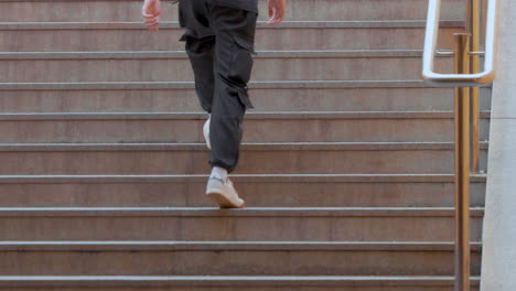 A-person-is-ascending-outdoor-steps,-captured-mid-stride,-focusing-on-the-lower-half-of-the-body
