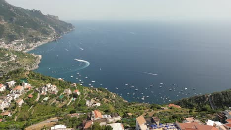 Drone-shot-over-Ravello,-Italy's-expansive-cliffs-overlooking-the-sea-on-a-sunny-day