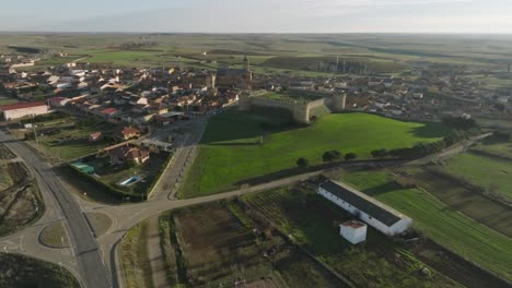 Aerial-Panoramic-Medieval-Castie-in-Spanish-town-rural-fields-Grajal-de-Campos-drone-establishing-panoramic-shot,-daylight-skyline