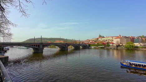 High-angle-shot-of-Charles-Bridge-over-Vltava-River-in-Prague-in-Czechia,-Prague,-Czech-Republic-on-a-sunny-day-with-tourist-boat-passing-by