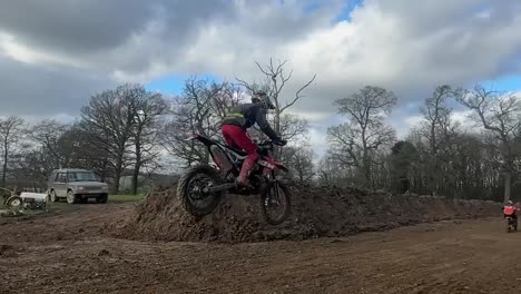 Vídeo-En-Cámara-Lenta-De-Un-Joven-Piloto-Profesional-De-Motocross-Saltando-En-La-Cima-De-Una-Colina-Grande-Y-Empinada-En-El-Campo-De-Inglaterra-Mientras-Compite-En-Una-Competición