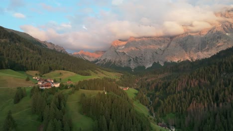An-evening-aerial-footage-of-secluded-houses-of-the-village-of-La-Val-with-majestic-Sas-dles-Nü-mountain-covered-in-beautiful-clouds-in-the-background
