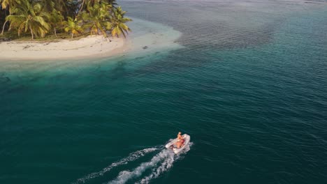 Sunset-drone-shot-of-3-young-guys-in-a-dinghy-in-San-Blas-Islands,-Panama