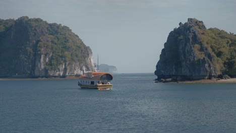 Vista-De-Drones-De-Paralaje-De-Un-Barco-Navegando-En-La-Bahía-Cerca-De-La-Isla-Cat-Ba-Y-Aguas-Turquesas,-Vietnam