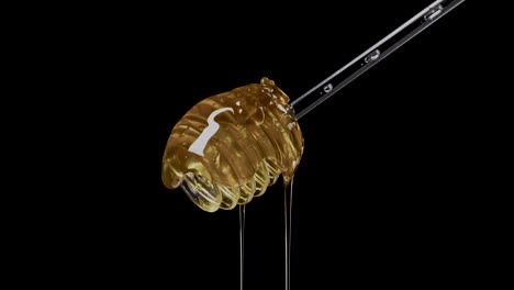 Organic-honey-flows-from-the-dipper,-against-a-backdrop-of-sleek-black,-the-honey-stick-immersed-in-the-golden-flow