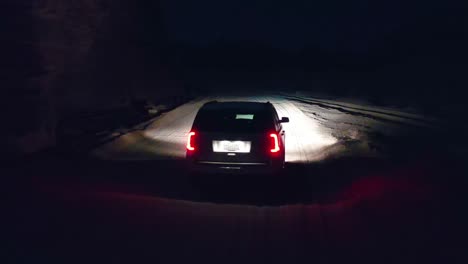 Aerial-drone-view-following-a-car-driving-on-a-desert-road,-in-pitch-black-darkness