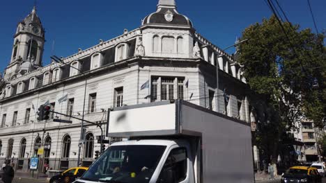 Rivadavia-Avenue-National-Argentine-Bank-traffic-drive-daily-transit-people-walk-pedestrians-at-flores-neighborhood,-skyline,-crossing-street,-san-Jose-de-flores-basilica