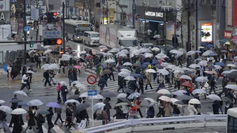Shibuya-Scramble-Square-Cruzando-Peatones-Bajo-La-Lluvia,-Tokio,-Japón