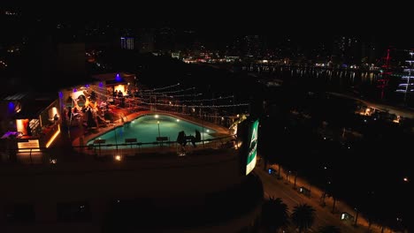 Aerial-drone-View-Of-Rooftop-Restaurant-Of-AC-Hotel-At-Night-In-Malaga,-Andalusia,-Spain