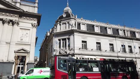 Banco-Nacional-De-Buenos-Aires-Argentina,-Avenida-Rivadavia-Tráfico-Por-Ciudad-Barrio-Flores,-Autobuses,-Peatones-Cerca-De-La-Basílica-San-José-De-Flores