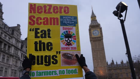 A-person-holds-up-a-placard-that-reads,-“NetZero-scam-“Eat-the-bugs