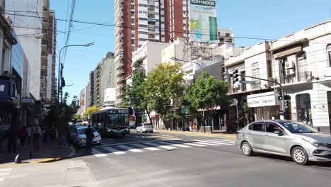 Traffic-at-Rivadavia-Avenue-neighborhood-people-architecture-buildings-under-sunny-skyline,-latin-American-capital-city