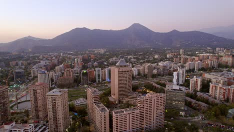 Drohnenansicht-Der-Andenkordilleren-Bergkette,-Talstadt-In-Santiago-De-Chile,-Vitacura-Und-Las-Condes,-Viertel,-Luftaufnahme-Mit-Farbenfroher-Skyline-Bei-Sonnenuntergang