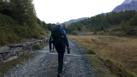 Male-Hiking-Along-Gravel-Path-With-Backpack-Holding-Camera-In-Valmalenco-Region,-Italy