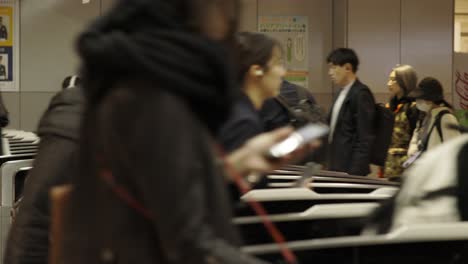 Shibuya-Train-Station,-Commuters-walking-through-ticket-gates,-Tokyo,-Japan