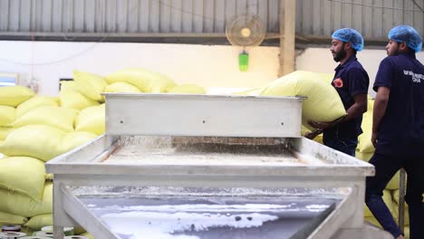 pov-shot-Bags-of-food-are-being-fed-into-a-machine-by-humans-to-clean-the-food