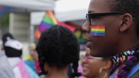 Un-Primer-Plano-De-Un-Asistente-Al-Festival,-Con-Una-Pegatina-De-La-Bandera-Del-Orgullo-En-La-Cara,-Durante-El-Festival-Del-Orgullo-A-Mitad-De-Camino