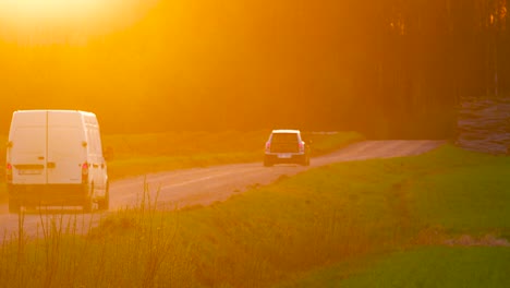 Los-Coches-Conducen-Lentamente-Por-Un-Pintoresco-Camino-De-Grava-Durante-El-Atardecer-Naranja-Brillante