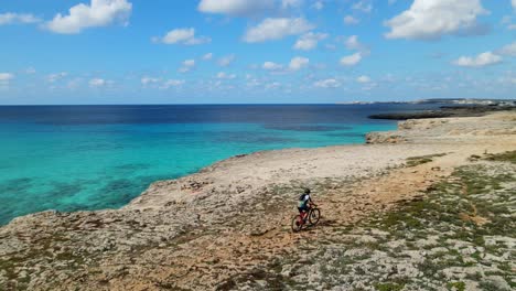 Primer-Plano-De-Un-Drone-Panorámica-Alrededor-De-Un-Ciclista-De-Montaña-A-Mitad-De-Carrera-A-Lo-Largo-De-La-Costa-De-España