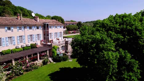 Drone-Traveling-to-a-Provençal-Mas:-Revealing-Blue-Shutters,-Green-Lawn,-Rose-Garden-and-Flower-Beds
