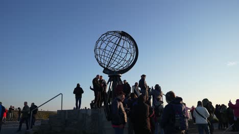 Menschen-Rund-Um-Das-Globus-Denkmal-Am-Nordkap,-Norwegen-Bei-Sonnenuntergang-60fps