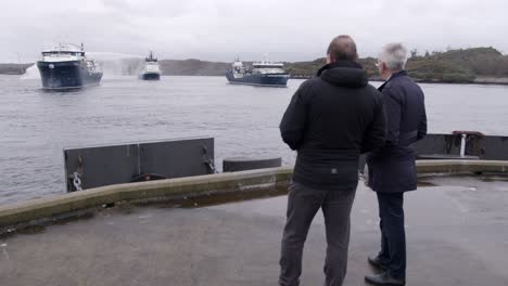 Slow-motion-shot-of-a-vessel-spraying-it's-water-cannon-as-two-individuals-watch-from-the-pier