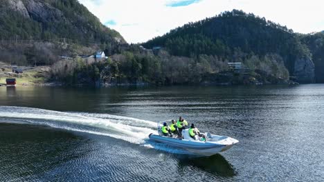 Drone-flies-low-and-fast-past-tour-boat-on-private-fjord-tour-in-Norway,-Veafjord