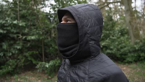 Young-hispanic-thug-with-mask-and-cap-in-black-jacket-standing-on-lookout