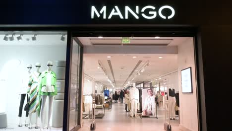 Käufer-Sind-Im-Geschäft-Der-Spanischen-Multinationalen-Bekleidungsmarke-Mango-Zu-Sehen,-Während-Ein-Fußgänger-In-Spanien-Am-Bild-Vorbeigeht