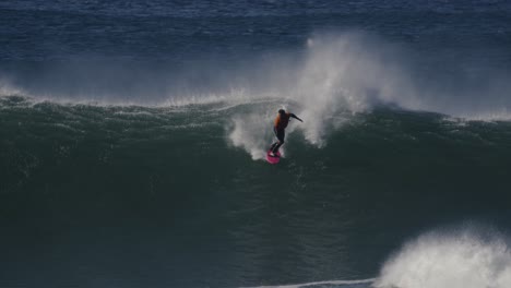 Toma-En-Cámara-Lenta-De-Un-Surfista-Montando-Una-Ola-Rompiendo-En-Una-Enorme-Masa-De-Espuma-Blanca