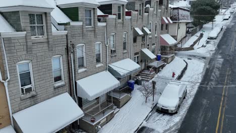 Absteigende-Drohnenaufnahme-Einer-Häuserreihe-Mit-Veranda-Während-Eines-Verschneiten-Wintertages