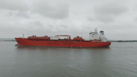 An-aerial-view-panning-from-right-to-left-of-an-ODFJELL-Tanker-passing-by-Morgan's-Point-under-gloomy-skies-in-the-Houston-Ship-Channel-in-Houston,-Texas