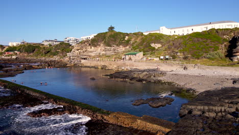 Ruhiges-Gezeitenbecken-Im-Meer-Mit-Menschen,-Die-Bei-Sonnenaufgang-Schwimmen,-Hermanus