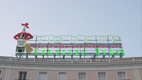The-neon-advertising-sign-of-Tio-Pepe,-a-symbol-of-Madrid-and-the-Puerta-del-Sol-,-is-representing-a-well-known-dry-sherry-wine,-also-called-Sol-de-Andalucia-embotellado,-in-Madrid,-Spain