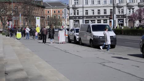 Toma-En-Cámara-Lenta-De-Turistas-Caminando-Por-La-Acera-Cerca-De-Un-Edificio-Antiguo-En-Viena,-Austria