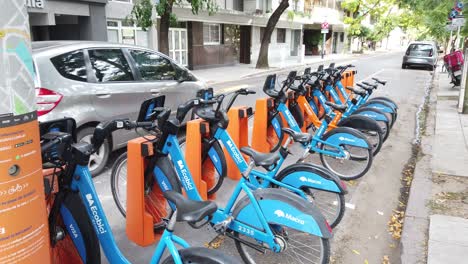Urban-city-bicycles-blue-orange-parking-spot-at-buenos-aires-street-service-free-transportation-in-argentina-latin-city-urban-panning-daylight-shot